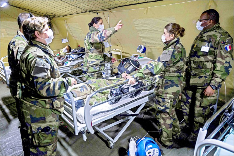 法國軍方24日在東北部米盧斯市艾米爾．米萊爾醫院外設立的臨時醫院演練防疫行動。（法新社）