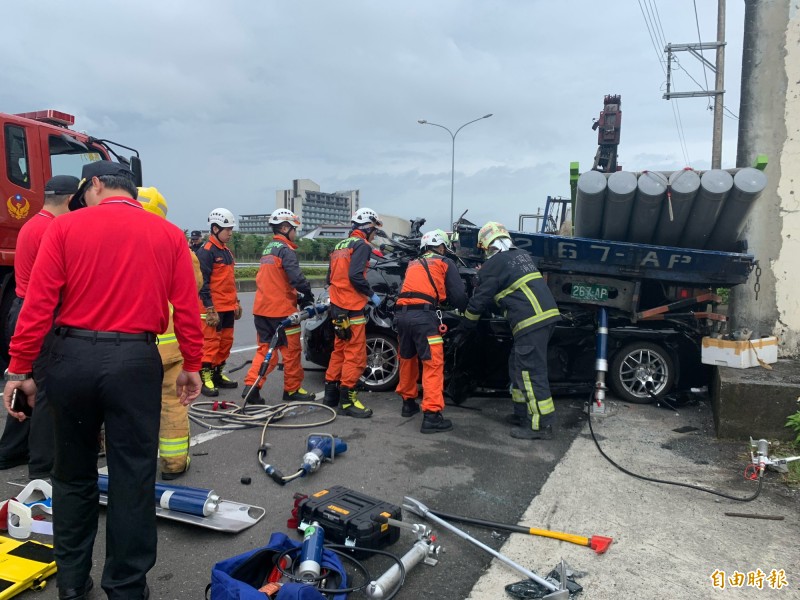 小客車被壓在大貨車下，消防人員搶救受困車上的2人。（記者林敬倫攝）