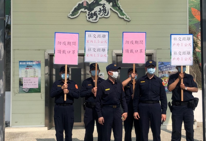 麻豆分局宣導隊4日在「國家級警報」示警的官田烏山頭水庫內的湖境度假會館前，舉牌向遊客宣導戶外保持安全的社交距離。（資料照）