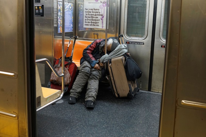 在紐約地鐵車廂裡熟睡的遊民。（路透）