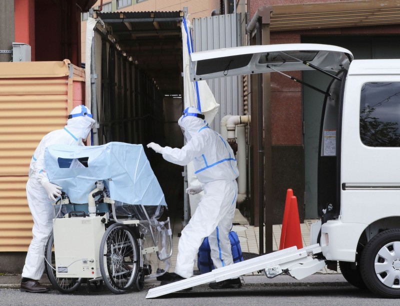 日本東京目前已有11起猝死後才驗出新型冠狀病毒的案例，其中7人是在發燒後7天至12天內死亡。圖為日本防疫人員運送病患。（路透）