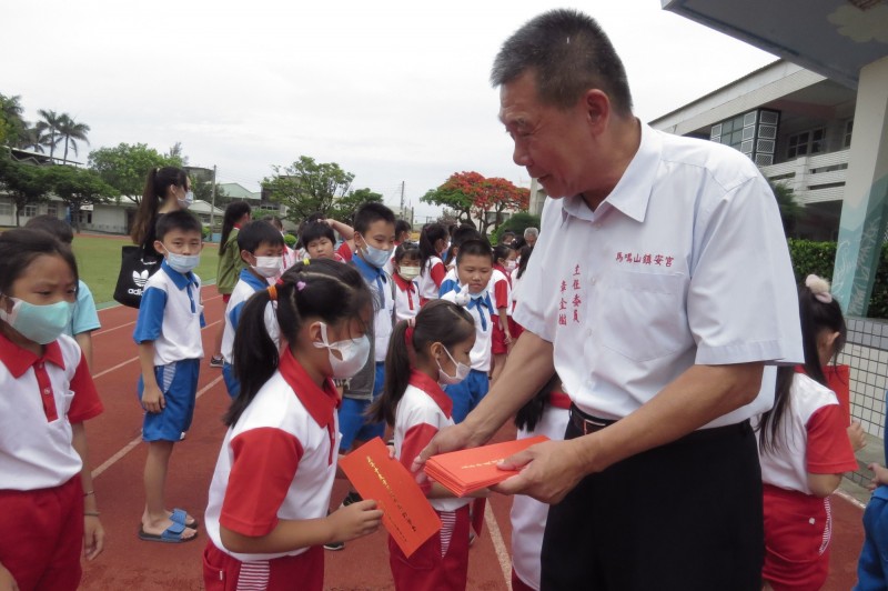 馬鳴山鎮安宮主委章金樹頒發獎助學金給學生。（記者林國賢翻攝）