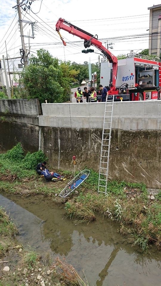 消防隊操作吊掛系統將籃式擔架垂下，將傷者從5米深的水溝拉上岸。（記者鄭名翔翻攝）