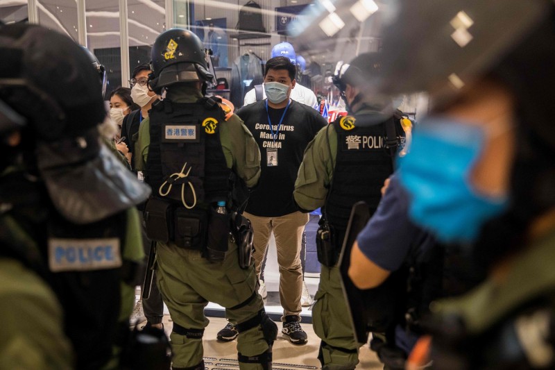 適逢香港元朗白衣人事件一周年，許多市民今天走上街頭，抗議警方縱容白衣人暴力攻擊示威者，香港警方指控79人涉嫌違反限聚令，另外逮捕5人。圖為香港警方盤查示威者。（法新社）