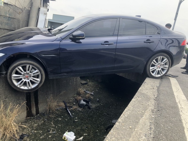 進口車飛躍排水溝，撞上農田工具間旁的電桿。（記者劉曉欣翻攝）