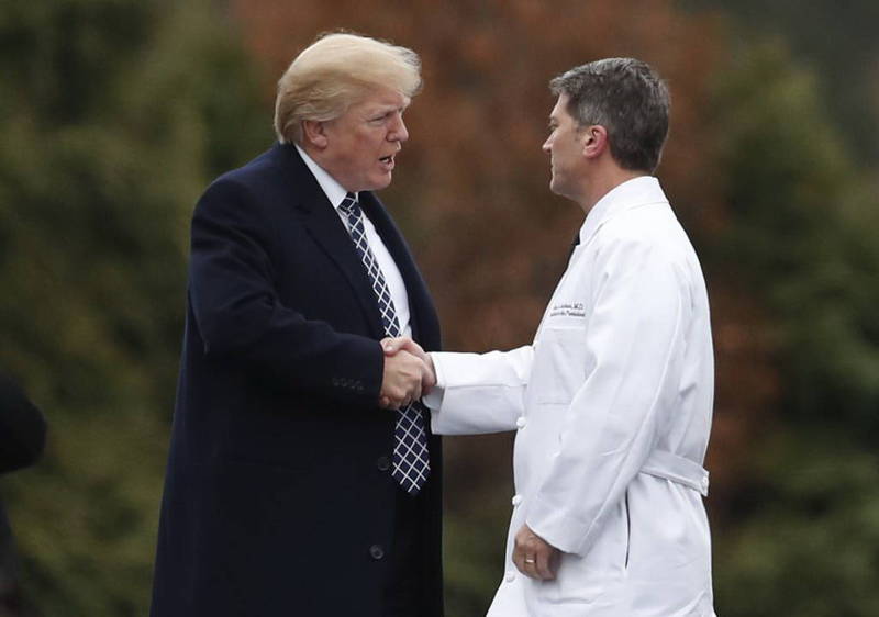 前白宮醫生傑克森（右）今天表示，美國總統川普是無症狀感染，圖為兩人在2018年握手問候的畫面。（美聯社）