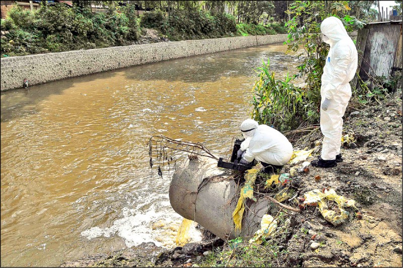 研究人員穿著防護裝，在加德滿都河水中採集污水樣本，檢驗新冠病毒。（法新社）