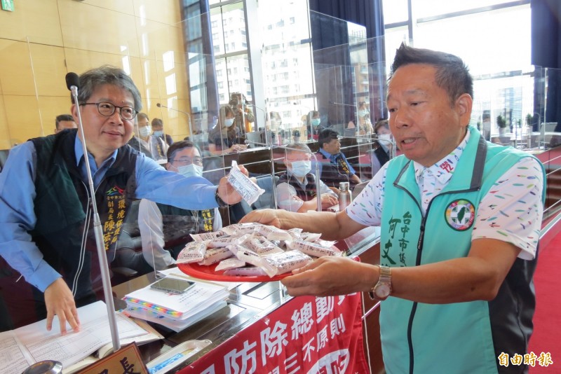 市議員何文海（右）拿出台中市老鼠藥給環保局副局長陳宏益看，他表示根本沒效，老鼠都不吃。（記者蘇金鳳攝）