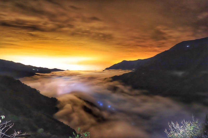 南投信義鄉望高地區出現雲海景致，夜間水氣累積，山下燈火映照雲霧透出琉璃光，展現夜間朦朧美感。（陳才毅提供）