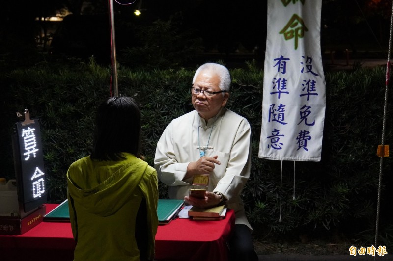 納骨塔旁的算命攤，成外勞的心靈加油站。（記者顏宏駿攝）