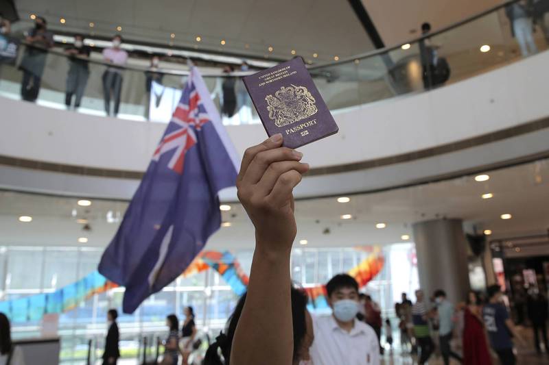 2020年5月一名香港示威者拿著BNO護照和英治時期旗幟，參與抗議國安法行動。（美聯社檔案照）