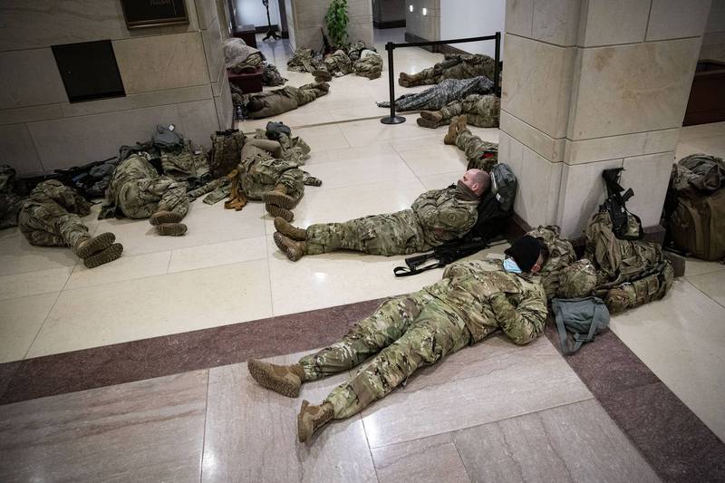 大批國民兵部隊在國會大廳和迴廊的地板上休憩或補眠，武器不離身。（彭博）