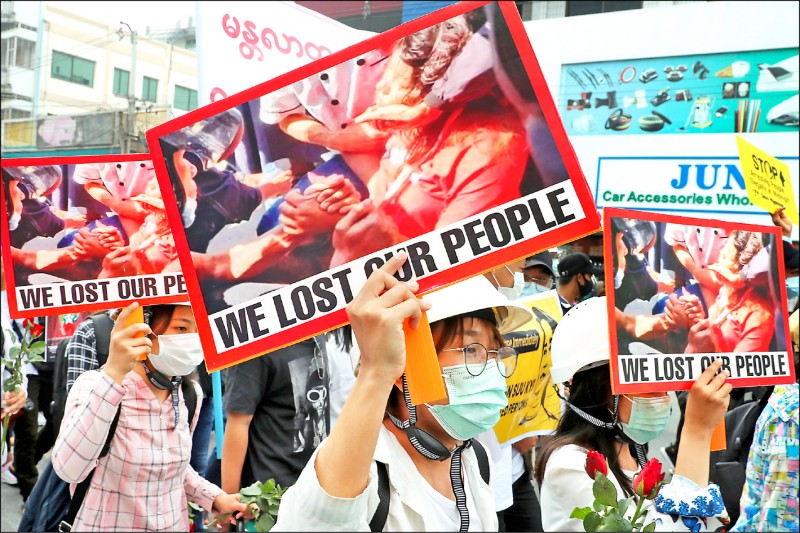 緬甸第二大城曼德勒民眾手持照片、追悼九日在首都奈比多遭橡膠子彈擊中頭部，十九日過世的反軍政府示威的首名死者。（美聯社）