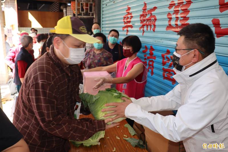 陳鴻源（右）在服務處賣高麗菜，民眾反應熱烈，大排長龍。（記者翁聿煌攝）