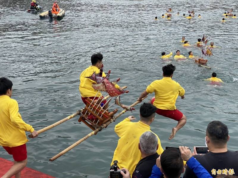 「新北神明淨港文化祭」今日早上在野柳保安宮前熱鬧登場，年輕力壯的野柳勇士抬著神轎，在眾人聲中，躍入野柳漁港，盼能藉由神尊法力讓漁船漁獲滿艙，讓疫情遠離。（記者俞肇福攝）