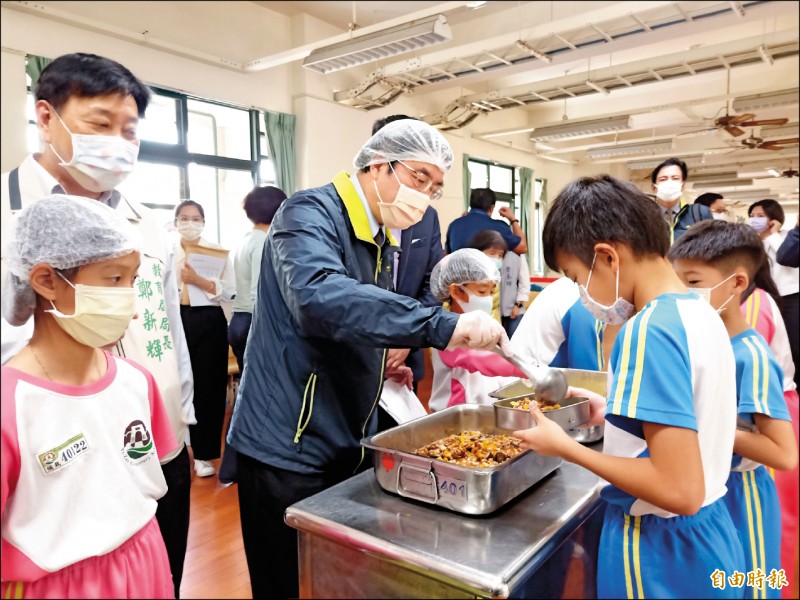 市長黃偉哲昨日前往學校視察食安廉政平台運作，並化身志工為學童打菜。（記者王姝琇攝）