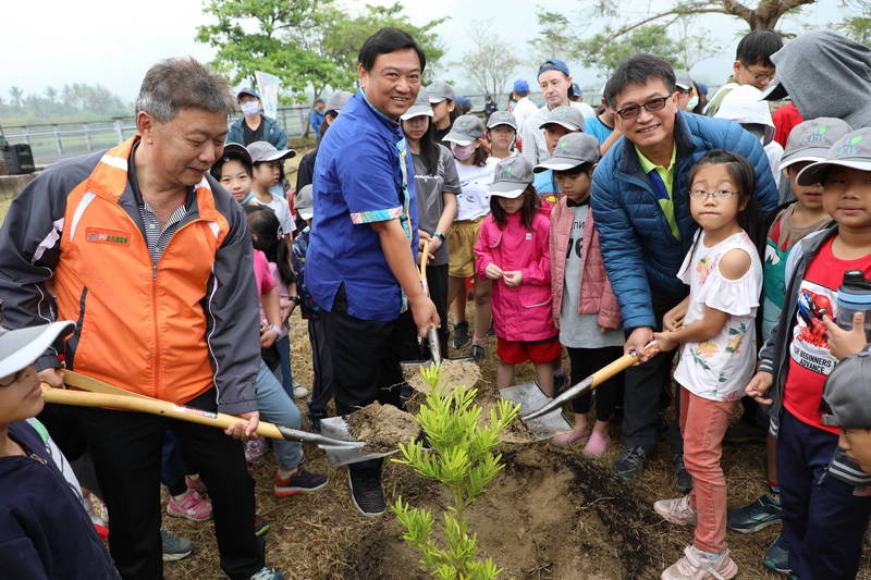 屏東林管處旗山工作站主任林弘基（左）、美濃區長鍾炳光（中）、東門國小校長宋雯榮（右）與學童們在美濃湖畔種下樹苗。（圖由屏東林管處提供）