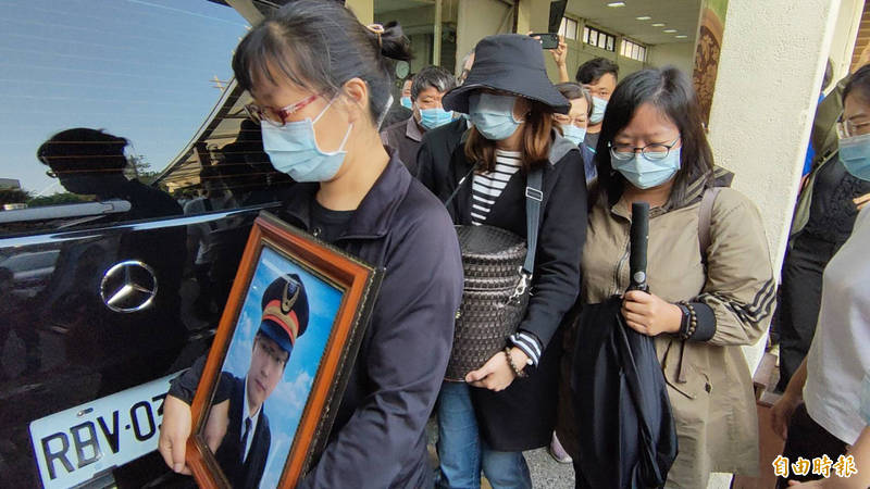 袁淳修妻子、二姊分別捧著骨灰罐及遺照下車。（記者許國楨攝）