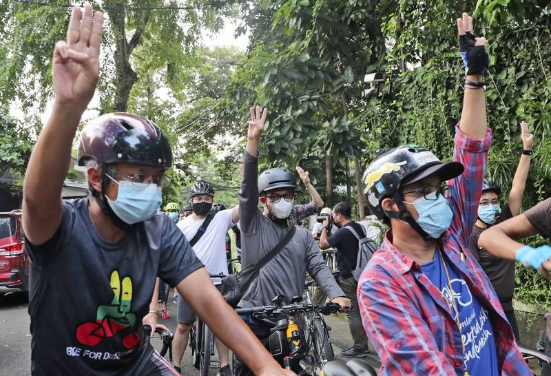 緬甸示威者騎摩托車及腳踏車遊行，高舉三指象徵革命及反抗極權統治。（美聯社）