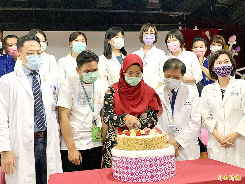 An Indonesian doctoral student, center, front row, surrounded by doctors and staff of Kaohsiung Medical University, and her husband, second left, yesterday cuts a cake to celebrate the birth of her child on Wednesday last week after receiving IVF treatment at the hospital.
Photo: Fang Chih-hsien, Taipei Times