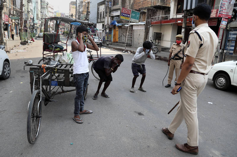 圖為14日印度阿薩姆邦古瓦哈提，警察在街上處罰違反防疫規定的民眾。（美聯社）