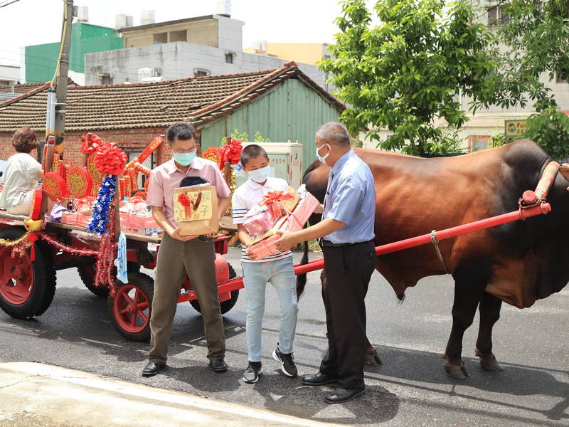 台南市安南區青草國小校長曾文欽（右），以牛車將畢業禮物宅配送到畢業生手上。（曾文欽提供）