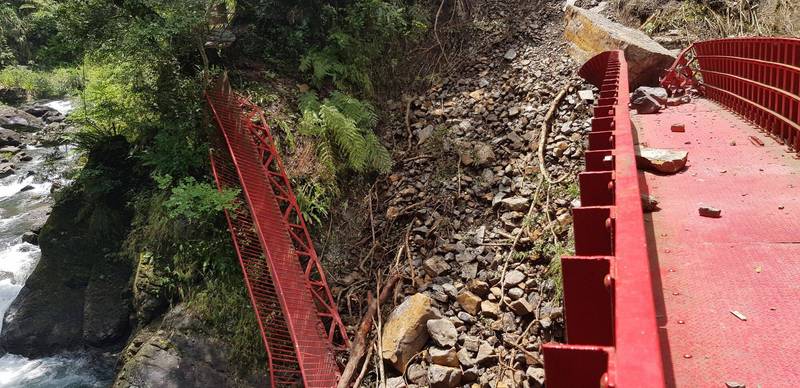 小烏來風景特定區的長虹橋，因邊坡崩落土石嚴重毀損，其中一側欄杆應聲倒下。（記者李容萍翻攝）