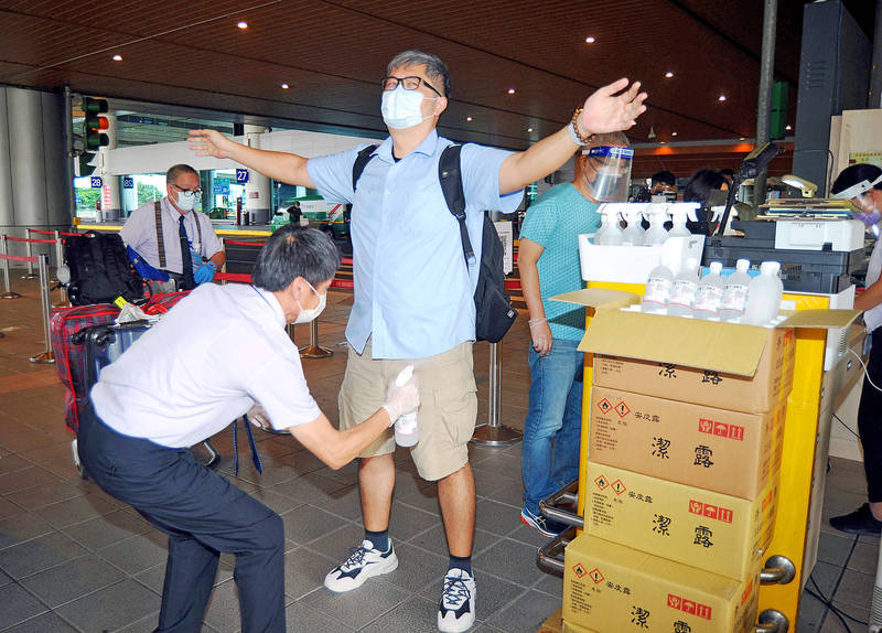 A worker at Taiwan Taoyuan International Airport sprays an arriving passenger yesterday.
Photo: CNA