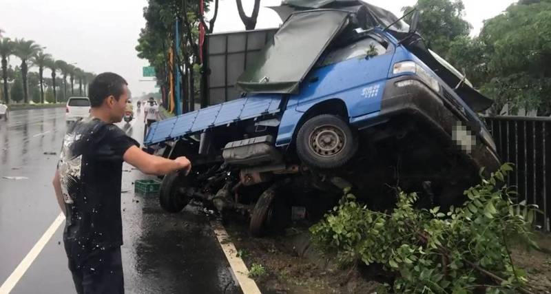 高屏大橋屏東端小貨車失控翻覆自撞電桿，駕駛人幸運爬出車外。（讀者提供）