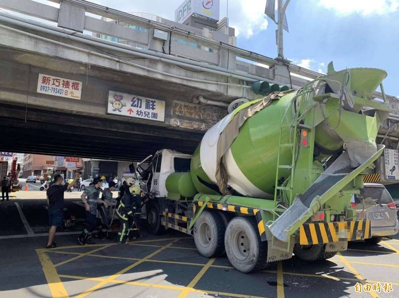 1輛預拌混凝土車今天行經彰化市中央陸橋下方的天祥路，硬闖後車頭整個壓在橋下。 （記者湯世名攝）