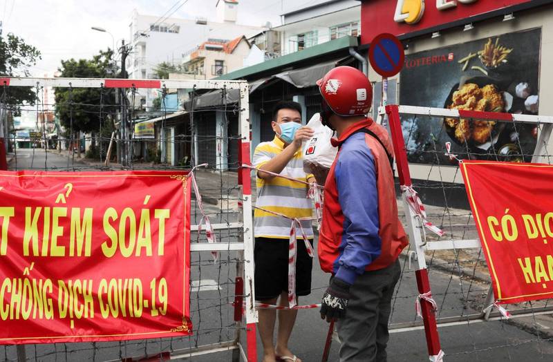 越南自7月23日通報首例台灣人在越南染疫死亡後，迄今共有5名台灣人因為確診在越南病逝，圖為胡志明市民在封城的情況下，透過圍籬取用外送的畫面。（資料照，路透）