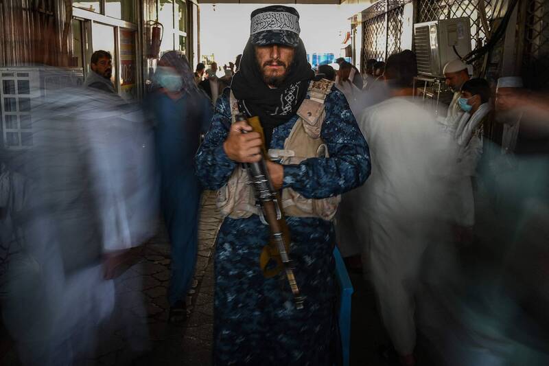 圖為9月5日塔利班士兵站崗，民眾從他身旁經過。（法新社）