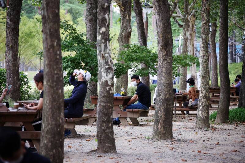 南韓民眾日前在首爾一座公園內休息，並保持社交距離。示意圖。（路透）
