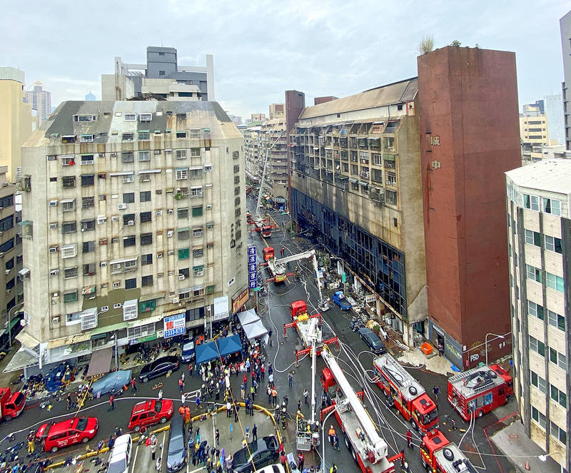 Fire engines and firefighters fill the street around the Cheng Chung Cheng building in Kaohsiung’s Yancheng District yesterday after extinguishing a huge fire that started in the early hours of yesterday morning.
Photo: CNA Fire engines and firefighters fill the street around the Cheng Chung Cheng building in Kaohsiung’s Yancheng District yesterday after extinguishing a huge fire that started in the early hours of yesterday morning.
Photo: CNA
