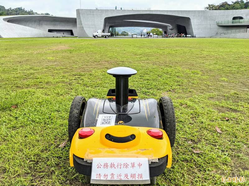日管處引進除草機器人測試效能，機身貼有「公務執行除草中」告示，提醒遊客切勿靠近。（記者劉濱銓攝）