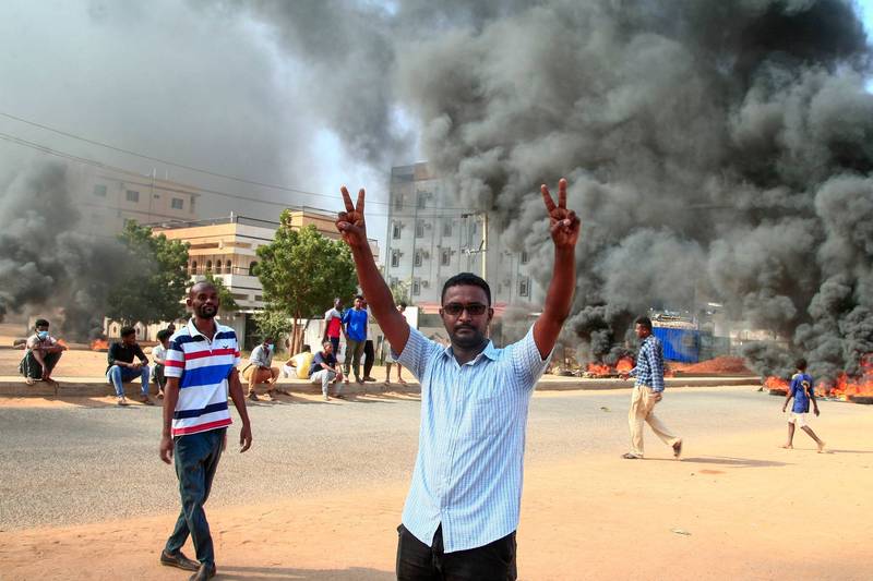 一名示威者在首都喀土穆街头比着胜利手势，他背后有大量黑烟升起。（法新社）(photo:LTN)