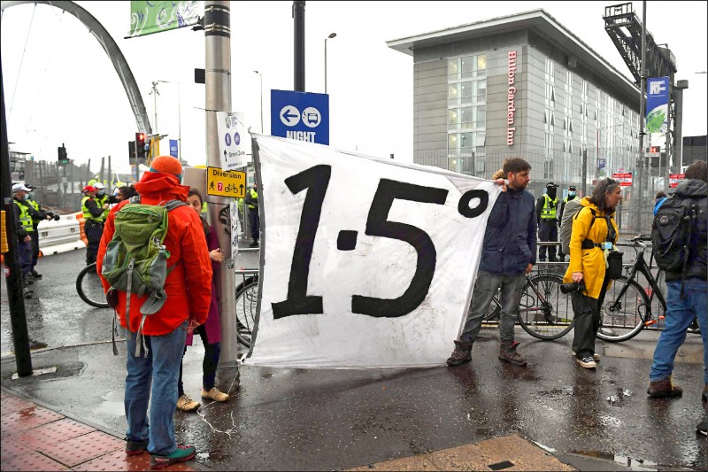 格拉斯哥十二日在会场外仍有抗议人士举写着一‧五的布条，要求各国必须遵守二○一五年巴黎协定将全球升温限制在比前工业时代高摄氏一‧五度的目标。（法新社）(photo:LTN)