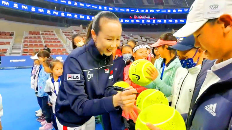 An image grab from a video appears to show Chinese tennis player Peng Shuai, left, signing large-sized tennis balls at the opening ceremony of the Fila Kids Junior Tennis Challenger Finals in Beijing yesterday.
Photo: Reuters via Twitter @qingqoingparis