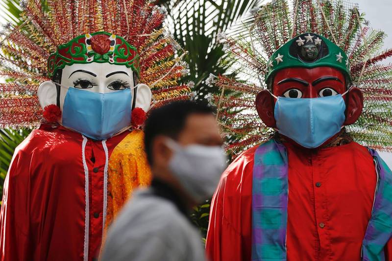 印尼今夏疫情延燒時，據稱能驅邪避凶的傳統大型人偶「Ondel-ondel」，都在遊街時戴上口罩。（路透）