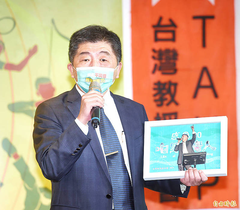 Minister of Health and Welfare Chen Shih-chung receives a photograph of himself singing during a fundraising event in Taipei yesterday.
Photo: Fang Pin-chao, Taipei Times