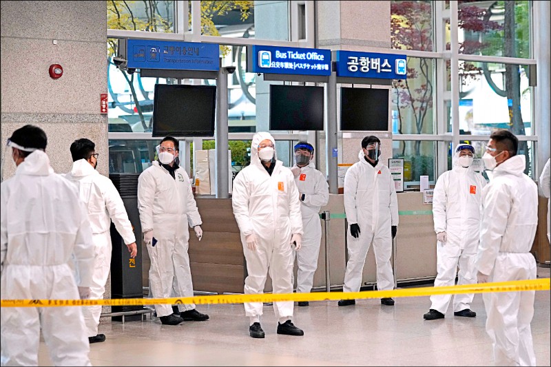 南韓仁川機場則有大批身著防護服的檢疫員在入境大廳等候為旅客做篩檢。（美聯社）