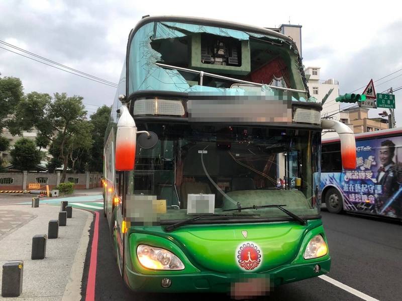 梁姓男子駕駛的遊覽車撞倒限高架，上方車體與車窗毀損。（警方提供）