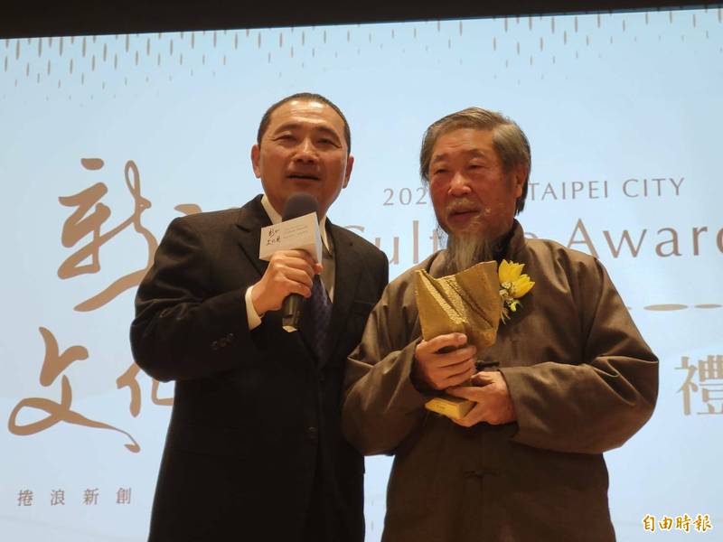 新北市長侯友宜早上出席新北文化獎頒獎典禮，圖為他頒獎給94歲的雕塑家李再鈐。（記者何玉華攝）