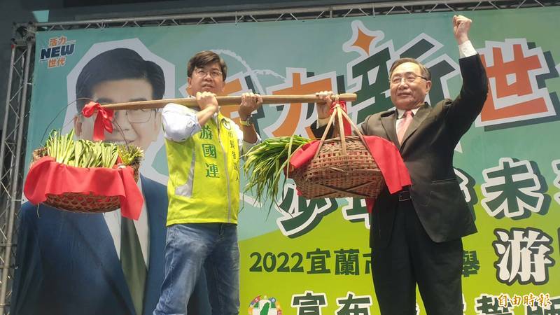 游國連（左）決定參選宜蘭市長，前縣長劉守成將象徵承擔責任的「扁擔」交給游國連，並祝福初選勝出「蔥滿勝蒜」。（記者游明金攝）