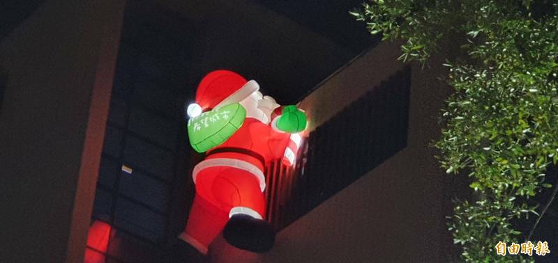 耶誕老人爬牆找不到煙囪，發現窗戶但擠不進去。（記者張聰秋攝）