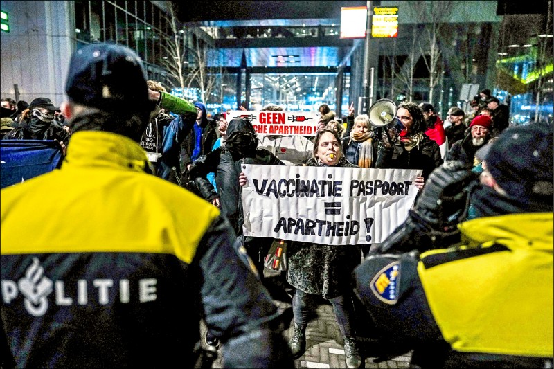 Omicron變種病毒來勢洶洶，荷蘭成為第一個重新進入嚴格全國封鎖的歐盟國家，耶誕及新年期間將執行最嚴厲防疫措施。荷蘭首相呂特與公衛官員十八日在海牙召開相關記者會時，場外示威民眾群情激憤，有人舉起「疫苗護照形同種族隔離」的抗議布條。（法新社）