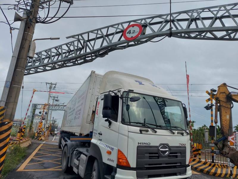 台鐵南迴線屏東縣潮州站至南州站間，今天下午因一輛卡車超高，卡在田寮路平交道限高門，南下、北上雙向列車一度無法通行。機具將闖越田寮路平交道的貨車拖離。（台鐵局提供）