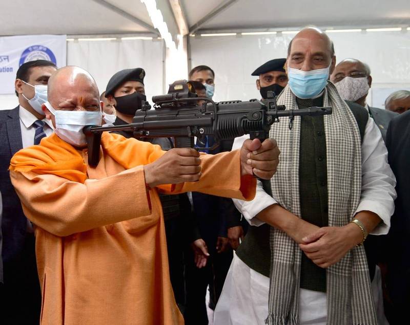 印度北方邦首长阿蒂提亚纳特（前左）近日出席军武展时拿起自动步枪摆姿势拍照，却把枪托靠在嘴上，一旁的国防部长辛格（前右）虽然戴着口罩，仍看得出表情有点尴尬。（图取自印度北方邦首长办公室官方推特）(photo:LTN)