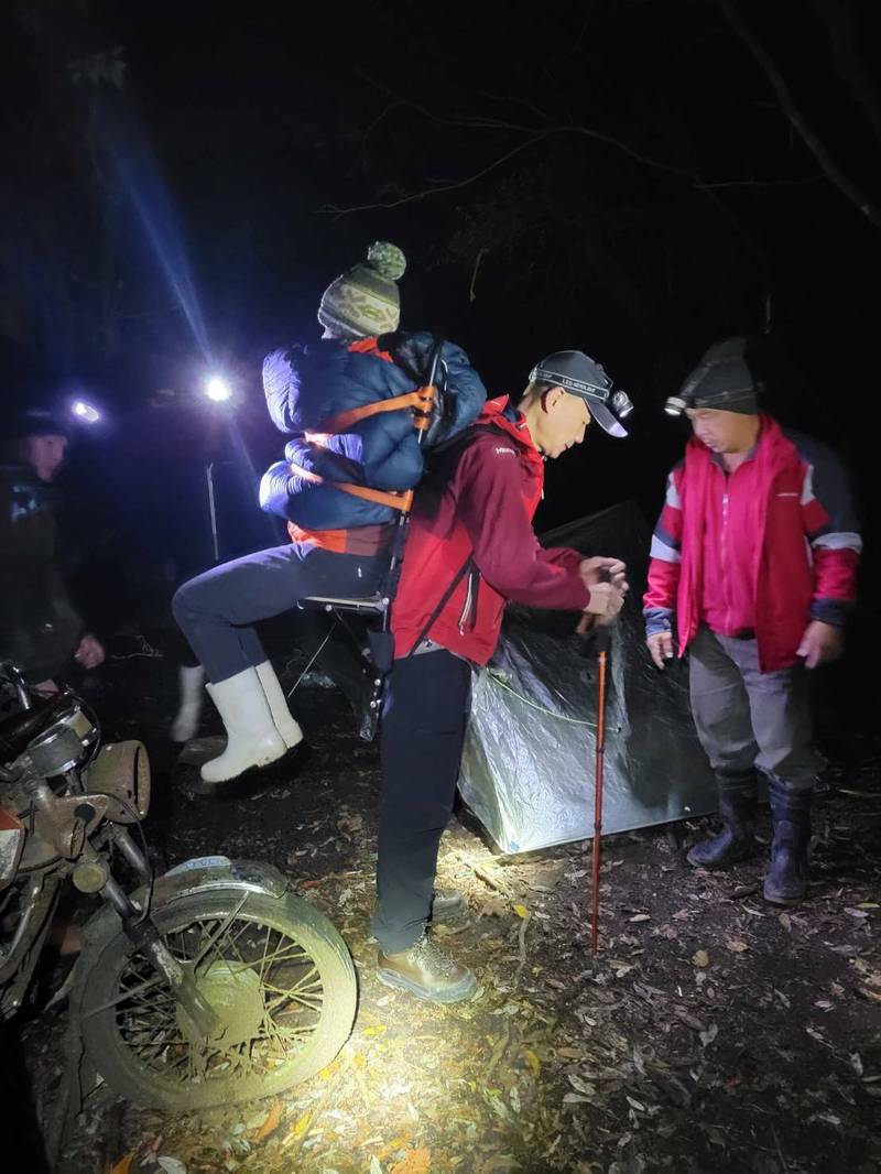 消防員將女子背負下山。（記者張軒哲翻攝）