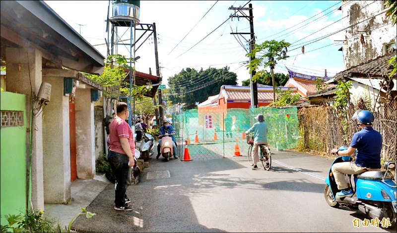 屏東市長春街孔廟路段被地主圍籬封掉大半路面，影響居民進出。（記者李立法攝）